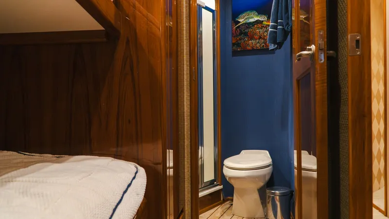 Slide: The Image of Guest Cabin and Ensuite Head This inviting guest cabin features warm wood finishes and a comfortable berth, complemented by the ensuite head. The bathroom boasts a sleek design with modern fixtures and a vibrant blue accent wall. Thoughtful details such as ambient lighting and a spac - 7943384
