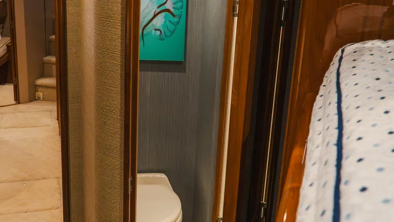 Slide: The Image of Guest Cabin with Ensuite Head This image showcases the guest cabin of the Viking 66 Convertible, featuring an ensuite head. The cabin is elegantly appointed with polished wood finishes and plush bedding. The head is compact yet functional, offering privacy and convenience for guests, - 7943379
