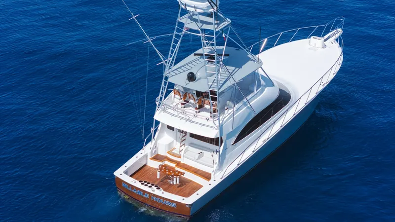 Slide: The Image of Aerial View of Aft Deck and Bridge This aerial shot showcases the expansive aft deck of the 2014 Viking 66 Convertible, 'Billable Hours'. The teak deck is complemented by a substantial fighting chair, ideal for sportfishing enthusiasts. Above, the flybridge offers commanding views with amp - 7943410