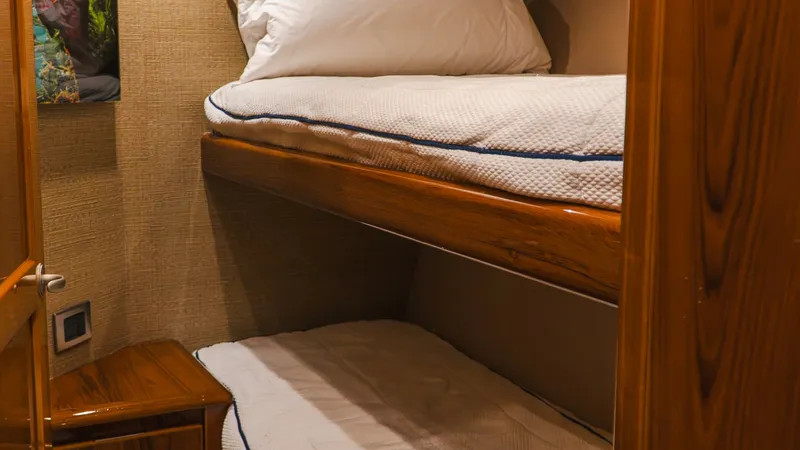 Slide: The Image of Cozy Twin Bunk Cabin This inviting twin bunk cabin on the 2014 Viking 66 Convertible offers practical and comfortable sleeping arrangements for guests. The warm wood finishes and soft bedding create a cozy atmosphere, while the efficient use of space ensures ample room for re - 7943381