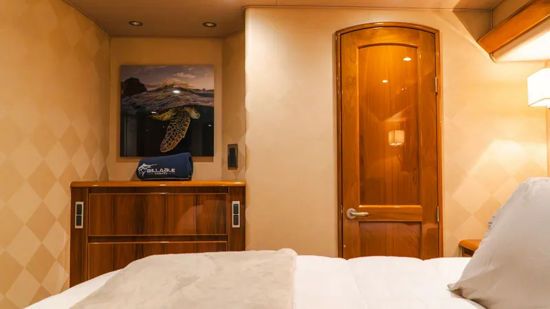 Slide: The Image of Master Stateroom with Elegant Woodwork This master stateroom on the 2014 Viking 66 Convertible showcases luxurious design with warm, rich wood finishes. The space features a plush bed with high-quality linens and ambient recessed lighting that enhances the cozy atmosphere. A polished wooden do - 7943372