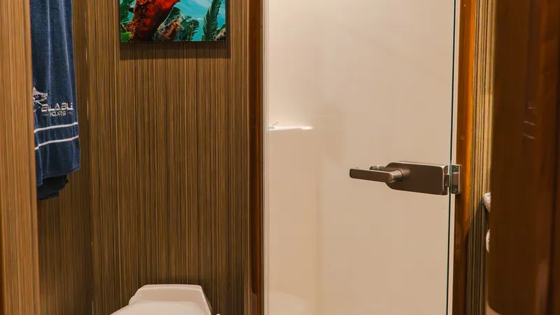Slide: The Image of Elegant Ensuite Bathroom This well-appointed ensuite bathroom features a sleek, modern shower with a glass door, complemented by rich wood paneling that exudes warmth and sophistication. The space is adorned with tasteful artwork and quality fixtures, providing a luxurious and co - 7943375