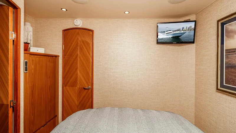 Slide: The Image of 2014 Viking 76 Enclosed Bridge "TRANQUILO" Guest Stateroom This cozy guest stateroom features a comfortable bed with elegant bedding, ideal for relaxation. The warm wood tones of the cabinetry and door add a touch of luxury, complemented by the modern wall-mounted TV for entertainment. Recessed lighting and taste - 7962484