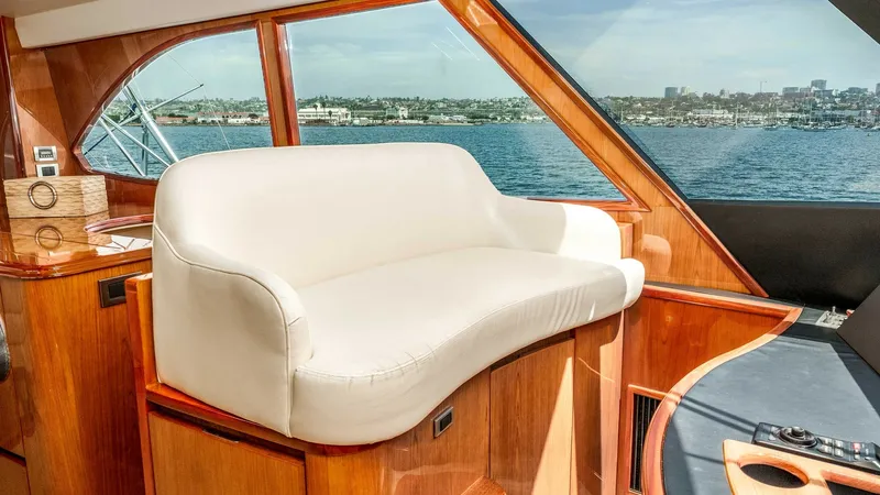 Slide: The Image of 2014 Viking 76 Enclosed Bridge "TRANQUILO" This image showcases the luxurious seating area within the enclosed bridge of the 2014 Viking 76 Enclosed Bridge Sportfisher, TRANQUILO. The plush, cream-colored upholstery contrasts beautifully with the rich wood finishes, offering a comfortable space fo - 7962470