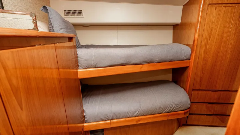 Slide: The Image of 2014 Viking 76 Enclosed Bridge "TRANQUILO" Bunk Cabin #1 This cozy guest cabin on the 2014 Viking 76 Enclosed Bridge Sportfisher features neatly arranged bunk beds, providing a comfortable and efficient sleeping space. The warm wood finishes and soft lighting create an inviting ambiance. Ample storage space, in - 7962486