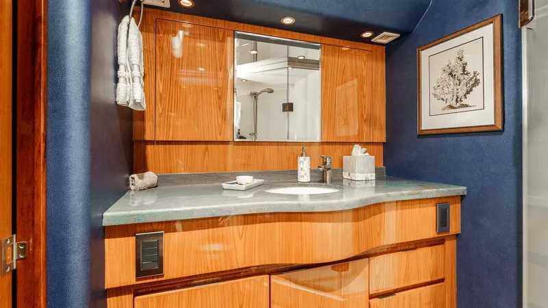 Slide: The Image of 2014 Viking 76 Enclosed Bridge "TRANQUILO" Master Stateroom Ensuite Head Vanity This image showcases the luxurious bathroom vanity aboard the Viking 76 Enclosed Bridge Sportfisher, TRANQUILO. The vanity features rich wood cabinetry and a sleek, polished countertop, complemented by ambient overhead lighting. Modern fixtures and a fram - 7962481