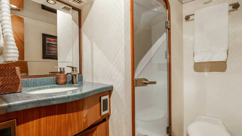 Slide: The Image of 2014 Viking 76 Enclosed Bridge "TRANQUILO" Bunk Cabin Ensuite Head This elegant guest bathroom on the Viking 76 Enclosed Bridge Sportfisher features a sleek glass-enclosed shower and stylish wood cabinetry. The contemporary sink area is complemented by a polished countertop and modern fixtures, creating a sophisticated a - 7962489