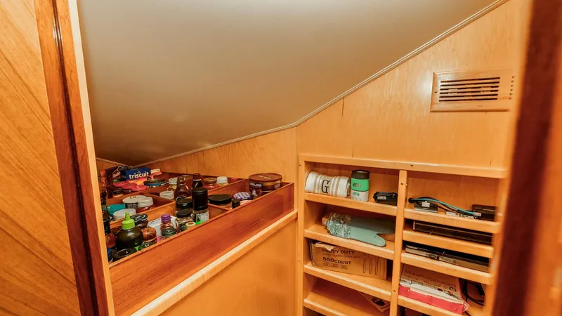 Slide: The Image of 2014 Viking 76 Enclosed Bridge "TRANQUILO" Lower Deck Storage This image showcases the well-organized pantry storage area aboard the 2014 Viking 76 Enclosed Bridge Sportfisher, TRANQUILO. The space is efficiently utilized with multiple shelves for easy access to provisions and essential items. The light wood finish - 7962474