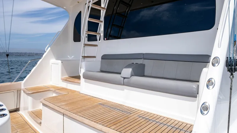 Slide: The Image of 2014 Viking 76 Enclosed Bridge "TRANQUILO" This inviting aft deck features a spacious seating area with plush gray cushions, perfect for relaxing while enjoying the sea views. The teak decking adds a touch of elegance and durability, complemented by polished stainless steel accents. The ladder lea - 7962511