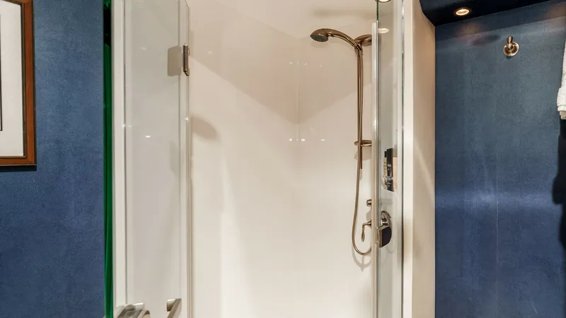 Slide: The Image of 2014 Viking 76 Enclosed Bridge "TRANQUILO" Shower Stall The shower stall in the Viking 76 Enclosed Bridge Sportfisher features a sleek modern design with a glass door and polished chrome fixtures. The white interior contrasts elegantly with the deep blue walls, creating a sophisticated and inviting space. Rece - 7962482