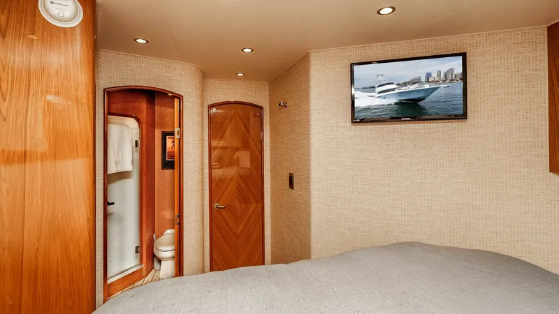 Slide: The Image of 2014 Viking 76 Enclosed Bridge "TRANQUILO" Forward Guest Stateroom This inviting guest stateroom on the Viking 76 Enclosed Bridge Sportfisher features a plush double bed and warm wood finishes. An ensuite bathroom is conveniently accessible, offering privacy and comfort. The room is equipped with modern amenities, includ - 7962493