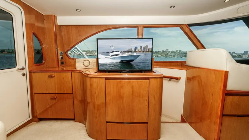 Slide: The Image of 2014 Viking 76 Enclosed Bridge "TRANQUILO" The enclosed bridge of the Viking 76 features a beautifully crafted entertainment area, complete with polished wood cabinetry and integrated storage. A flat-screen TV is centrally positioned, offering stunning views of the water through large surrounding - 7962468