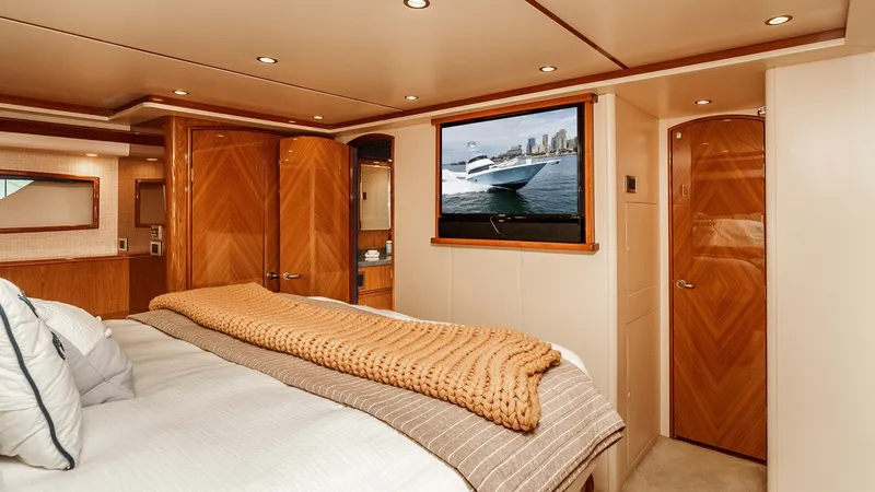 Slide: The Image of 2014 Viking 76 Enclosed Bridge "TRANQUILO" Master Stateroom This luxurious master stateroom features a plush queen-size bed adorned with elegant linens and a cozy throw. The space is complemented by rich wood finishes, recessed lighting, and ample storage, creating a warm and inviting atmosphere. A flat-screen TV - 7962480