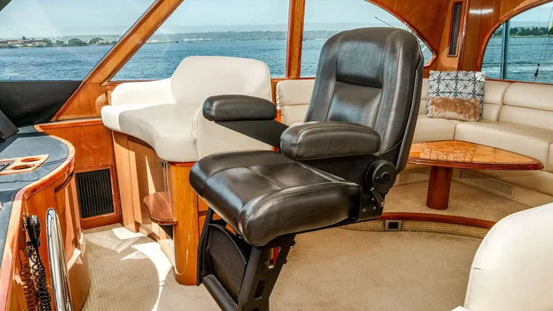 Slide: The Image of 2014 Viking 76 Enclosed Bridge "TRANQUILO" This image showcases the luxurious helm seating area of the Viking 76 Enclosed Bridge Sportfisher. The captain's chair is upholstered in premium leather, providing comfort and style, while the panoramic windows offer stunning views of the surrounding seas - 7962471