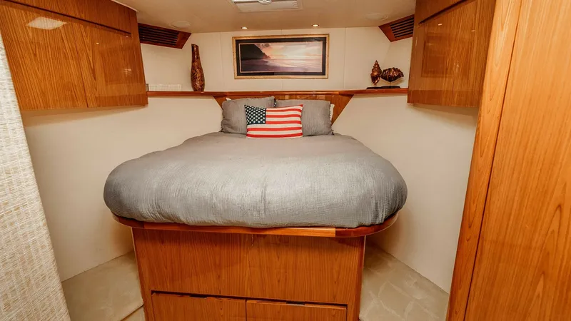 Slide: The Image of 2014 Viking 76 Enclosed Bridge "TRANQUILO" Forward Guest Stateroom This inviting forward cabin features a plush queen berth complemented by rich wood finishes and ample overhead storage. The soft ambient lighting and a skylight provide a cozy atmosphere, creating an ideal retreat for relaxation. Decorative accents and cl - 7962492