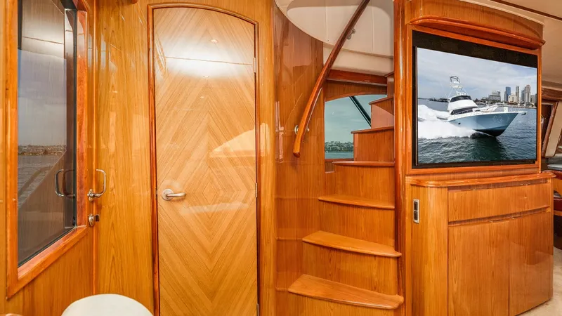 Slide: The Image of 2014 Viking 76 Enclosed Bridge "TRANQUILO" This image showcases the elegant staircase leading to the enclosed bridge of the 2014 Viking 76 Sportfisher. The beautifully crafted woodwork exudes luxury, complemented by the sleek, integrated entertainment unit featuring a large screen. The warm tones - 7962467
