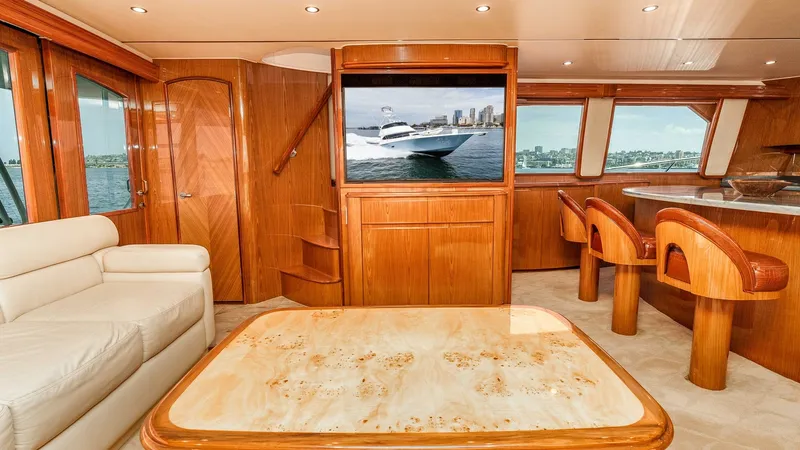 Slide: The Image of 2014 Viking 76 Enclosed Bridge "TRANQUILO" Custom Wood Salon with Stairway to Enclosed Bridge This photo shows the salon's aft area aboard the 2014 Viking Enclosed Bridge, with the custom teak coffee table and comfortable leather seating continuing the warm, classic interior. The rich wood cabinetry surrounds the entertainment center, while the in - 7962465