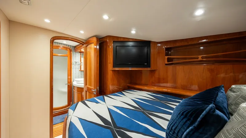 Slide: The Image of Luxurious Guest Stateroom This elegant guest stateroom on the 2008 Blue Angel 62 Sportfish by Winter Custom Yachts features rich wood finishes and plush bedding for ultimate comfort. A wall-mounted TV provides entertainment, while the ensuite bathroom offers modern amenities. Soft - 7961715
