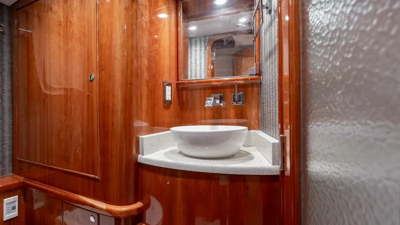Slide: The Image of Elegant Guest Head with Vessel Sink This guest head features a stylish vessel sink atop a polished countertop, set against exquisite high-gloss wood cabinetry. The mirrored medicine cabinet and ambient lighting enhance the space, adding both functionality and sophistication. The rich wood t - 7961716