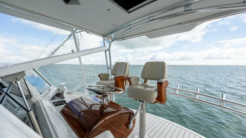 Slide: The Image of Flybridge Helm Station with Seating The flybridge of the 2008 Blue Angel 62 Sportfish by Winter Custom Yachts offers a commanding view, equipped with dual helm chairs featuring plush upholstery and polished wood accents. A sleek console provides intuitive controls, enhancing the captain's e - 7961704