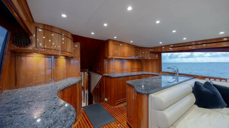 Slide: The Image of Galley and Lounge Area The interior features a luxurious galley equipped with elegant granite countertops and rich wood cabinetry, providing a warm and inviting atmosphere. The ample seating area with plush cushions offers comfort and style, complemented by panoramic views thro - 7961712