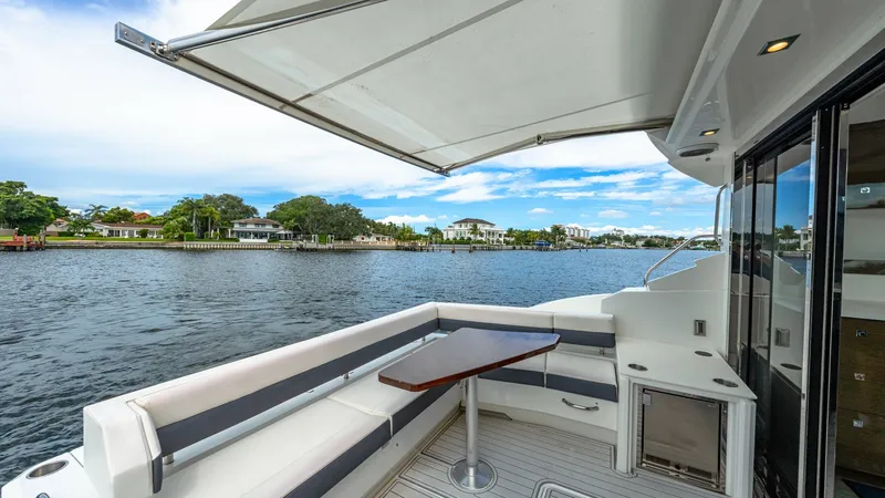 Slide: The Image of Spacious Cockpit with Seating Area The cockpit of the 2019 Cruisers Yachts Cantius 46 features a stylish and comfortable seating area, perfect for relaxing or entertaining guests. The L-shaped bench provides ample seating, complemented by a sleek, adjustable table. Overhead, a retractable - 8141265
