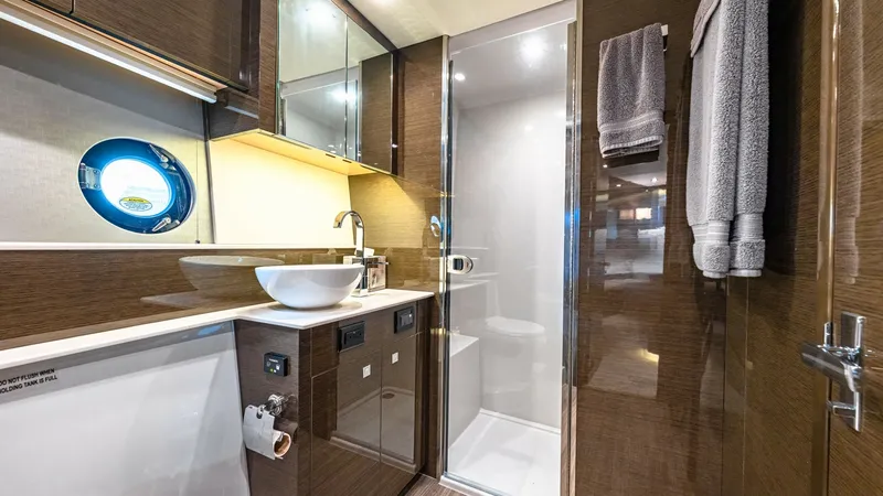 Slide: The Image of Luxurious Bathroom with Shower This elegant bathroom on the 2019 Cruisers Yachts Cantius 46 features a sleek, modern design with high-gloss wood finishes and a spacious shower enclosure. The vessel sink sits atop a polished countertop, complemented by ample storage behind mirrored cabi - 8141257
