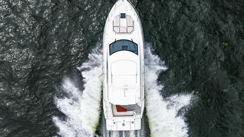 Slide: The Image of Aerial View of Serenity Underway This aerial shot captures the 2019 Cruisers Yachts Cantius 46, Serenity, gliding through the water with elegance. The vessel's sleek design is highlighted by its spacious sunpad on the bow, perfect for relaxation. The dynamic wake showcases the yacht's po - 8141315