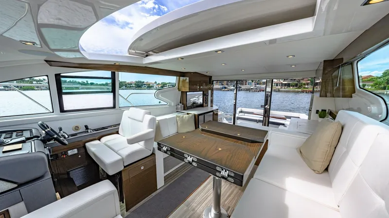 Slide: The Image of Spacious Interior Salon with Helm The interior salon of the 2019 Serenity Cantius 46 showcases a luxurious open layout with panoramic windows offering stunning views. Featuring a sophisticated helm station with ergonomic seating, the space is designed for both relaxation and navigation. T - 8141246