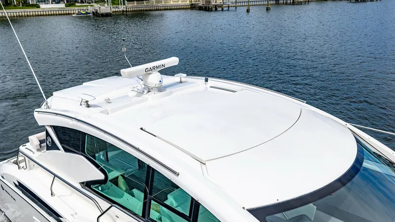 Slide: The Image of Flybridge Roof with Radar System The flybridge of the 2019 Cruisers Yachts Cantius 46 features a sleek, aerodynamic design equipped with a Garmin radar system. Its smooth, white finish enhances the vessel's modern aesthetics while providing efficient functionality. The expansive windows - 8141286
