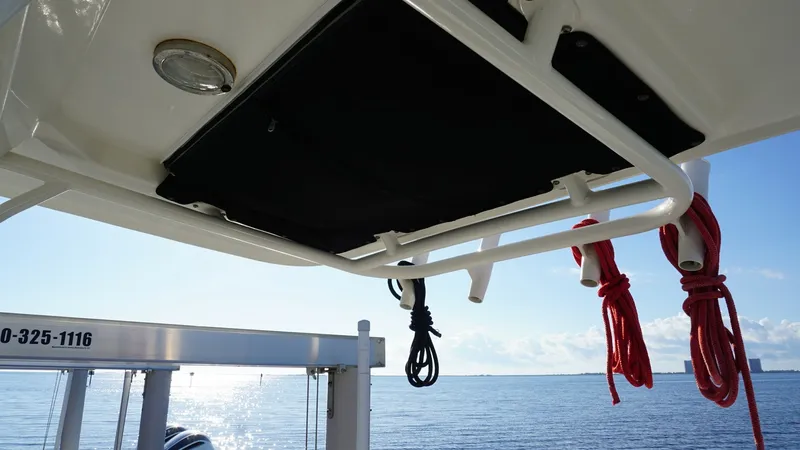 Slide: The Image of Hardtop with Rod Holders The Boston Whaler 270 Dauntless features a robust hardtop equipped with integrated rod holders, ideal for fishing enthusiasts. The hardtop provides ample shade and protection from the elements, while the neatly stored ropes add to the vessel's organized a - 8087576