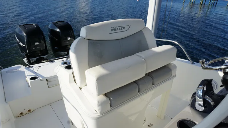 Slide: The Image of Helm Seat and Cockpit Area The image showcases the helm seat and surrounding cockpit area of the 2016 Boston Whaler 270 Dauntless. The seating is plush and features a sturdy backrest, providing comfort for extended outings. Nearby, the twin Mercury outboard engines hint at the vess - 8087566