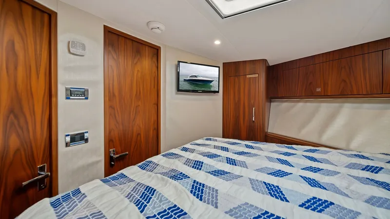 Slide: The Image of Master Stateroom with Skylight The master stateroom of the 2017 Hatteras GT45X showcases a spacious layout with rich wood finishes and modern amenities. A prominent skylight enhances natural lighting, while the comfortable bedding adds a touch of elegance. The room is equipped with amp - 8439537