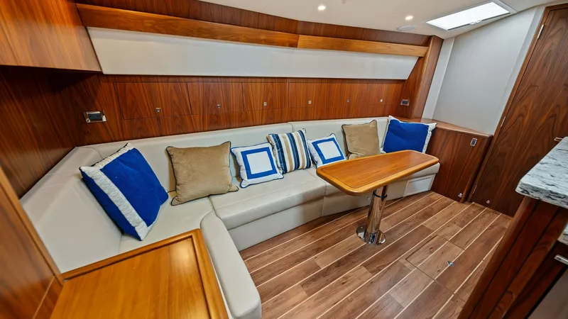 Slide: The Image of Salon with Elegant Dinette Seating This inviting salon on the 2017 Hatteras GT45X features a stylish dinette area with plush seating and decorative pillows, perfect for relaxation and dining. The rich wood finishes and sleek table design create a warm and sophisticated ambiance. Ample natu - 8439529
