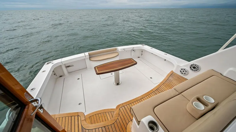 Slide: The Image of Spacious Aft Deck with Seating The aft deck of the 2017 Hatteras GT45X offers a spacious area for relaxation and entertainment, featuring a well-crafted wooden table and cushioned seating. Elegant teak flooring complements the sleek design, enhancing the luxurious feel of this outdoor - 8439553