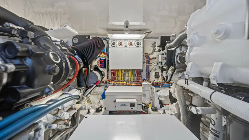 Slide: The Image of Engine Room with Advanced Systems The engine room of the SEA'N ME TOO showcases a meticulously organized space featuring state-of-the-art systems. The Hatteras GT45X's robust engineering is evident with its neatly arranged wiring and easy-access panels. Efficient layout and modern equipme - 8439559