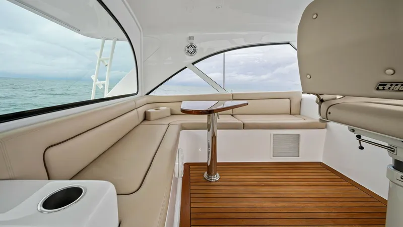 Slide: The Image of Enclosed Cockpit Seating Area This inviting enclosed cockpit on the 2017 Hatteras GT45X features plush, wraparound seating with elegant beige upholstery, perfect for socializing or enjoying the view. The polished wooden table adds a touch of sophistication and functionality to the spa - 8439549