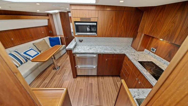 Slide: The Image of Galley and Dinette Area The galley of the 2017 Hatteras GT45X features elegant wood cabinetry and sleek granite countertops, complemented by modern stainless steel appliances including an oven and microwave. The adjoining dinette offers a cozy seating arrangement with plush cush - 8439516