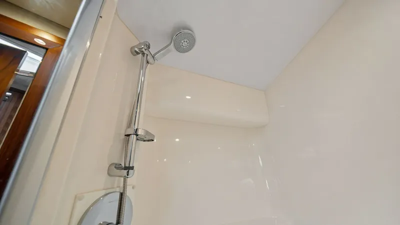 Slide: The Image of Modern Shower Enclosure This image showcases the sleek shower enclosure on the Hatteras GT45X. The space features a polished chrome adjustable shower head and minimalist controls, set against a pristine, high-gloss finish that exudes luxury. Recessed lighting enhances visibility - 8439535