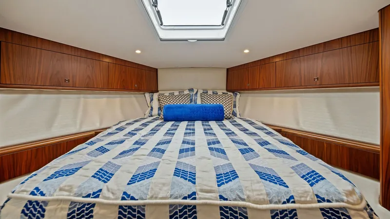 Slide: The Image of Forward Cabin with Skylight This inviting forward cabin on the 2017 Hatteras GT45X features a plush double berth adorned with a stylish blue and white patterned duvet. The space is enhanced by rich wood cabinetry, providing ample storage and a touch of elegance. A skylight above flo - 8439540