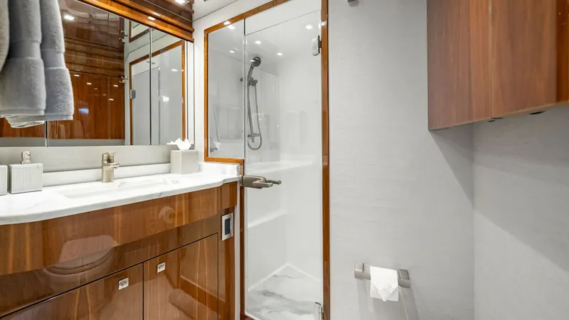 Slide: The Image of Luxurious En-Suite Bathroom This elegant en-suite bathroom features high-gloss wood cabinetry and a sleek marble countertop. The spacious glass-enclosed shower offers modern fixtures, providing a spa-like experience. Ample storage, sophisticated lighting, and premium finishes create - 8439620