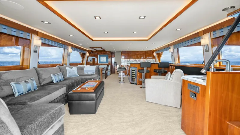 Slide: The Image of Luxurious Salon with Panoramic Views This spacious salon on the Viking 92 Enclosed Bridge offers a blend of elegance and comfort. Featuring plush seating, rich wood finishes, and large windows, the area is designed for relaxation and entertaining. The ambient lighting enhances the luxurious - 8439572