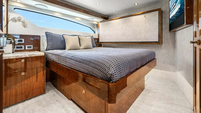 Slide: The Image of Luxurious Guest Stateroom with Ocean View This elegant guest stateroom on the 2017 Viking 92 Enclosed Bridge offers a serene retreat. It features a plush double bed adorned with stylish bedding, complemented by finely crafted wood cabinetry that provides ample storage. The large window floods the - 8439602