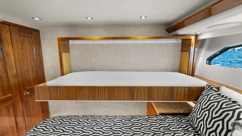 Slide: The Image of Stateroom with Convertible Bunk This elegant stateroom on the 2017 Viking 92 Enclosed Bridge features a cleverly designed convertible bunk. The room boasts high-quality wood finishes and ample natural light from a well-placed window, creating a warm and inviting atmosphere. The modern g - 8439608