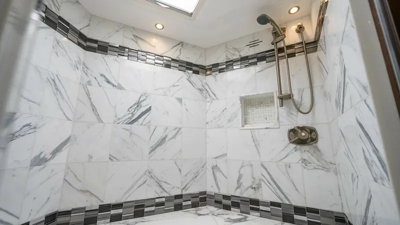 Slide: The Image of Luxurious Marble-Tiled Shower This elegant shower on the Viking 92 Enclosed Bridge features exquisite marble tiling with a striking pattern, creating a sophisticated and modern look. Equipped with a high-end adjustable showerhead and built-in niche for convenience, the space is both f - 8439618