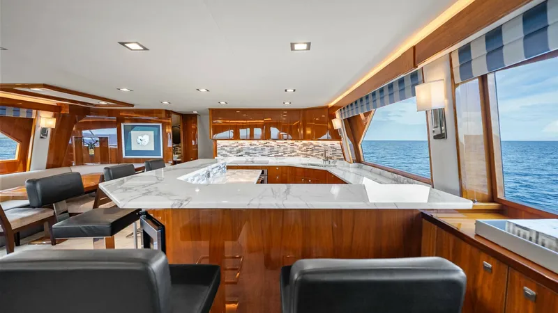 Slide: The Image of Elegant Salon with Marble Bar This luxurious salon on the Viking 92 Enclosed Bridge features a stunning marble-topped bar, perfect for entertaining guests. The rich wood finishes complement the modern decor, creating a warm and inviting atmosphere. Large windows offer panoramic ocean - 8439579