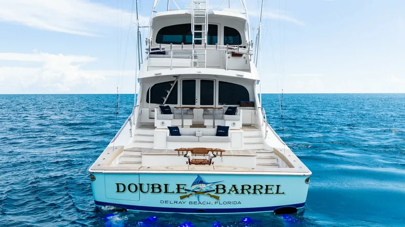 Slide: The Image of Aft Deck with Transom Seating The aft deck of the 2017 Viking 92 Enclosed Bridge, 'Double Barrel', offers ample transom seating with plush cushions for relaxing at sea. The spacious deck is equipped with a central fighting chair, perfect for sportfishing enthusiasts. Elegant teak fini - 8439645