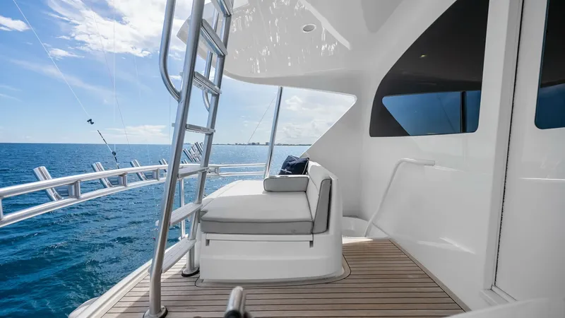 Slide: The Image of Aft Deck with Ladder Access This image showcases the aft deck of the 2017 Viking 92 Enclosed Bridge, featuring a sleek teak flooring that complements the yacht's modern design. The deck offers comfortable seating and easy access to upper levels via a sturdy ladder. Expansive ocean v - 8439594