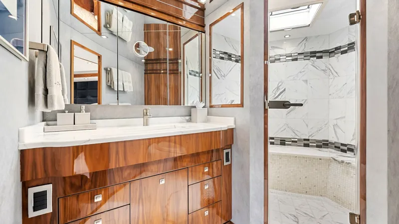 Slide: The Image of Luxurious En-Suite Bathroom Interior This elegant en-suite bathroom on the Viking 92 Enclosed Bridge features a beautifully crafted wooden vanity with ample storage and a sleek, modern design. The spacious shower area is adorned with stunning marble tiles and a glass enclosure, creating a lu - 8439617