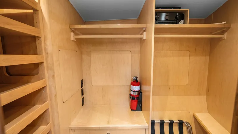 Slide: The Image of Utility and Storage Area This image showcases the practical utility and storage area of the Viking 92 Enclosed Bridge. Featuring sleek wooden cabinetry and shelving, it provides ample space for organizing essential equipment and supplies. The area is well-lit, making it easy to a - 8439623